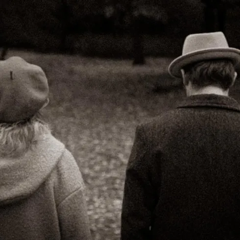 Ein Paar läuft in einem herbstlichen Park. Die Szene ist in sepia Farben gehalten, was eine nostalgische Stimmung erzeugt.