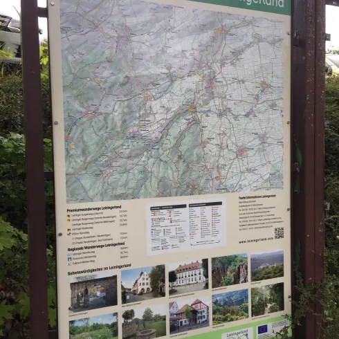 Ein Informationsschild mit einer Karte der Wanderwege im Leiningenland. Darunter sind Fotos und Informationen zu verschiedenen Sehenswürdigkeiten in der Region.