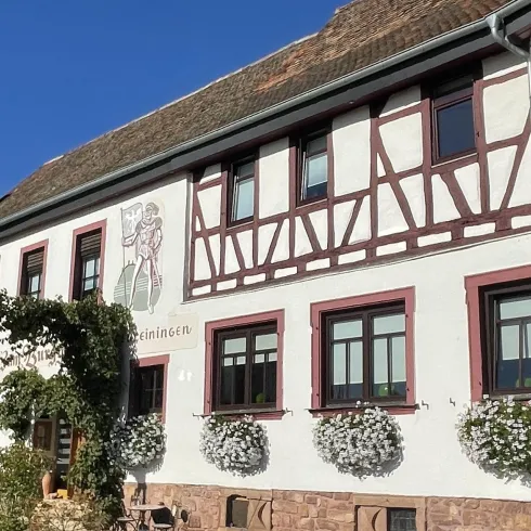 Ein historisches Fachwerkhaus mit bunten Fensterrahmen. Blumenkästen schmücken die Fenster und die Fassade strahlt Gemütlichkeit aus.