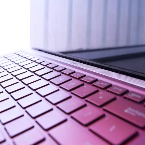 Ein Laptop mit einer modernen Tastatur ist im Bild zu sehen. Die Farben sind in sanften Tönen gehalten und der Fokus liegt auf der Tastatur.