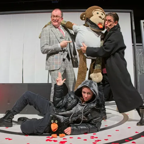 Eine humorvolle Theateraufführung mit vier Darstellern. Ein großer, kuscheliger Affe und farbenfrohe Kostüme sorgen für eine lebendige Atmosphäre.