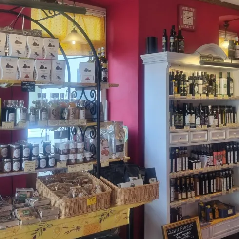 Ein einladendes Geschäft mit Regalen voller öl und Feinkostartikeln. Die Wände sind in einem warmen Rot gestrichen und schaffen eine gemütliche Atmosphäre.