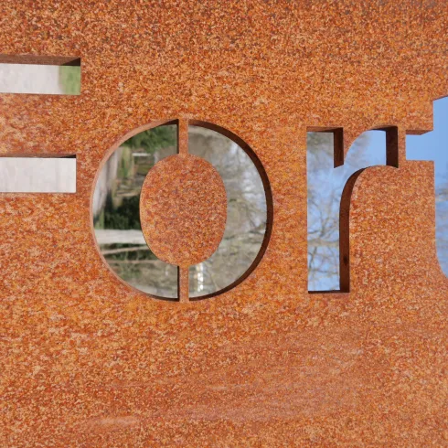 Ein metallisches Schild mit dem Wort "Fort" in großen Buchstaben. Der Hintergrund ist rostig und strukturiert.