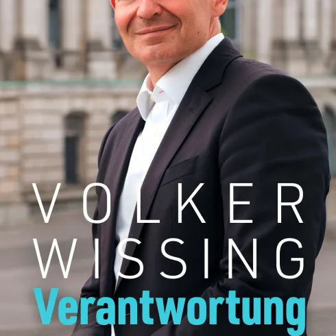 Ein Mann steht lächelnd vor einem historischen Gebäude. Der Name "Volker Wissing" und das Wort "Verantwortung" sind deutlich sichtbar.