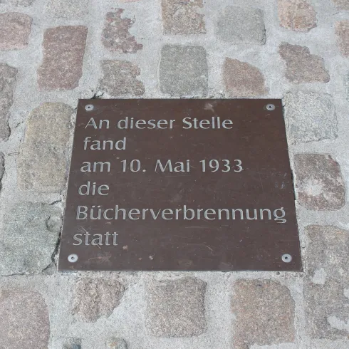 Eine Gedenktafel auf einem Pflastersteinboden. Sie erinnert an die Bücherverbrennung am 10. Mai 1933.
