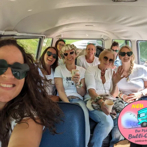 Eine Gruppe von Frauen sitzt in einem VW-Bus und lächelt in die Kamera. Alle genießen die fröhliche Stimmung.