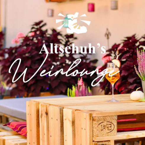 Eine gemütliche Weinlounge mit Holzmöbeln und bunten Pflanzen. Auf den Tischen stehen dekorative Blumen und ein Getränk.