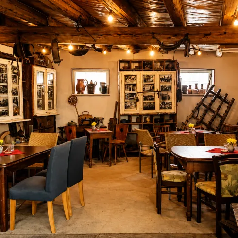 Ein gemütliches Café mit holzigem Interieur und warmem Licht. An den Wänden hängen nostalgische Fotografien und es stehen Tische mit Blumenvasen.