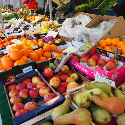 Ein bunter Marktstand mit einer Vielzahl von frischem Obst. Äpfel, Birnen und Orangen sind auf Tischen und in Kartons angeordnet.