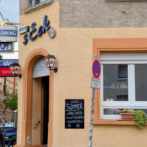 Ein einladendes Restaurant mit dem Namen "s'Eck". An der Wand hängt eine Tafel mit dem Hinweis auf das sommerliche Angebot.