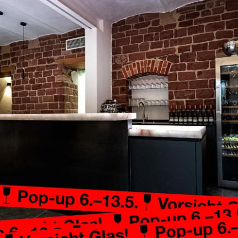 Eine moderne Bar mit Holz- und Steinwänden. Im Hintergrund sind Weinschränke und eine Anrichte zu sehen.