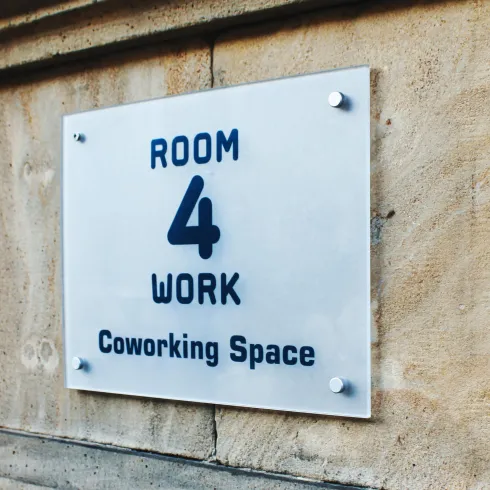 Ein Schild mit der Aufschrift "ROOM 4 WORK" und "Coworking Space". Es zeigt den Bereich für gemeinsames Arbeiten.
