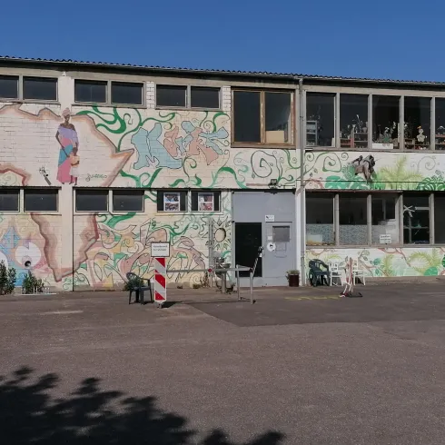 Ein Gebäude mit bunten Wandmalereien. Der Himmel ist klar und blau.