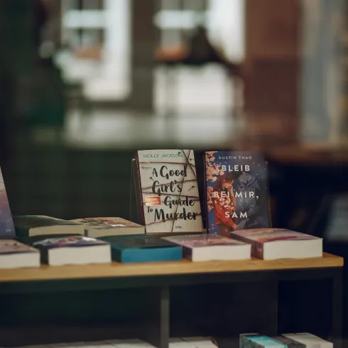 Ein Schaufenster mit einer Auswahl an Büchern. Einige Titel sind gut sichtbar, während andere in verschiedenen Farben angeordnet sind.