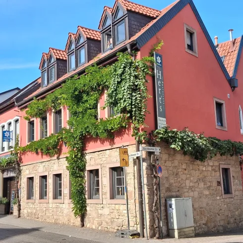 Ein charmantes Gebäude mit roter Fassade und begrünten Wänden. Die Architektur kombiniert moderne und traditionelle Elemente.