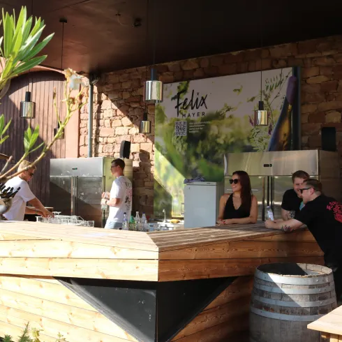 Eine helle Bar mit einem Holztrestaurant und freundlichem Personal. Im Hintergrund ist eine steinerne Wand und eine große Anzeige zu sehen.