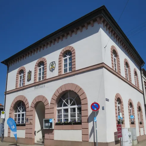 Ein historisches Gebäude mit einem auffälligen Fassadenstil und großen Fenstern. Es befindet sich an einer Straßenecke mit Verkehrsschildern in der Nähe.