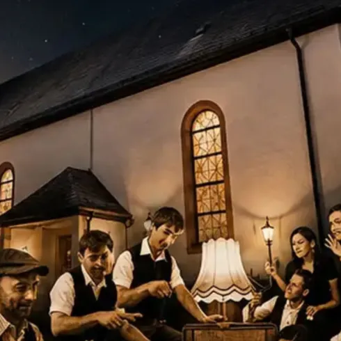 Die Bandmitglieder von "Die Üblichen Verdächtigen" sitzen vor einer Kirche in der Nacht, umgeben von warmem Licht. Sie wirken entspannt und freundlich.