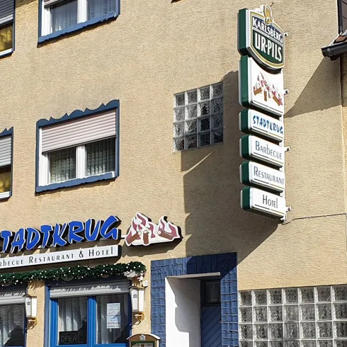 Ein charmantes Hotelgebäude mit verschiedenen Fenstern und einem auffälligen Schild. Die Fassade ist teilweise mit Pflanzen bewachsen.