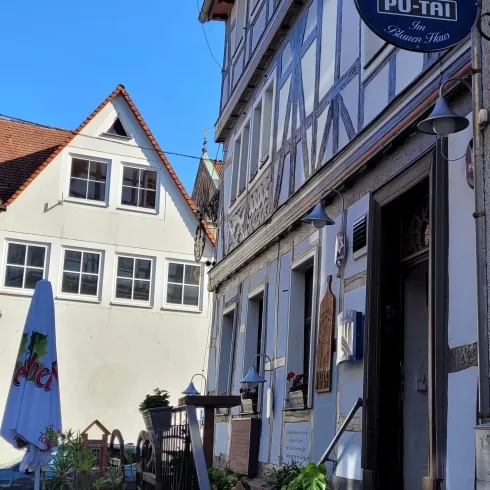 Ein charmantes Hotel mit einem historischen Fachwerkhaus und klar blauem Himmel. Die Umgebung ist einladend und gepflegt.