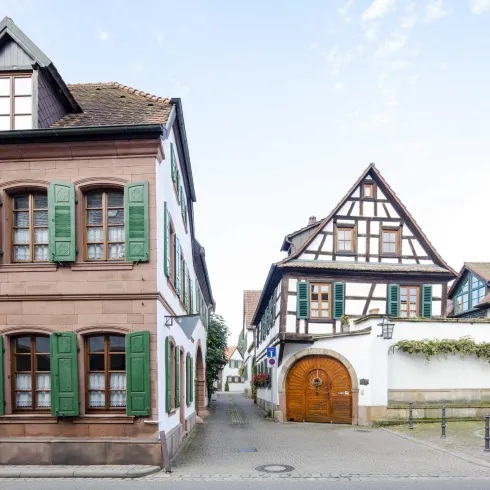 Eine ruhige Straße mit traditionellen Häusern in einem deutschen Ort. Die Gebäude sind mit grünen Fensterläden und charmanten architektonischen Details ausgestattet.
