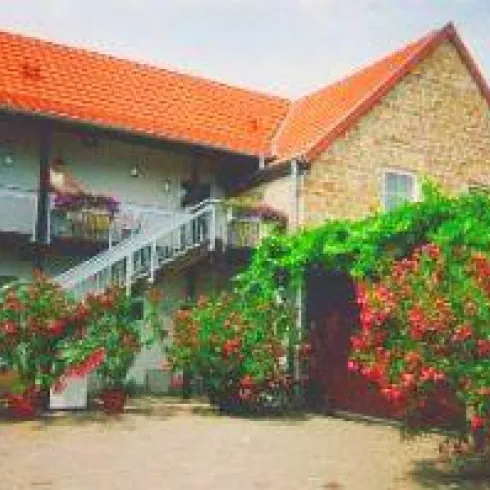 Ein schöner, rustikaler Bauernhof mit roten Dächern und Blumen. Der Eingangsbereich ist von bunten Pflanzen umgeben.