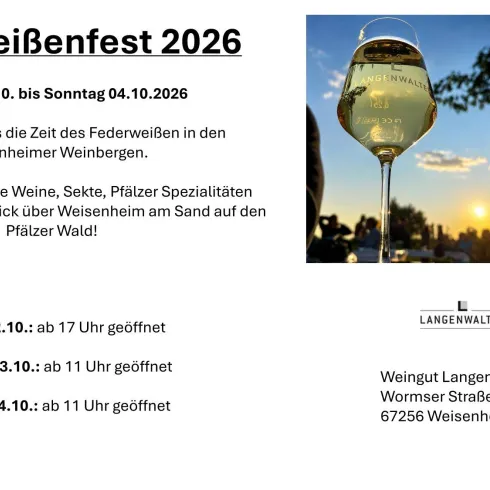 Ein Weinglas mit Weißwein und Gäste sitzend an Tischen im Freien.