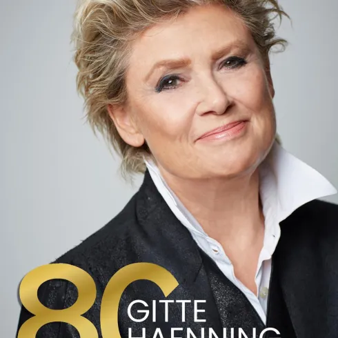 Eine Porträtaufnahme einer lächelnden Frau mit blonden, lockigen Haaren. Im Vordergrund steht "80 GITTE HAENNING TOUR 2026".
