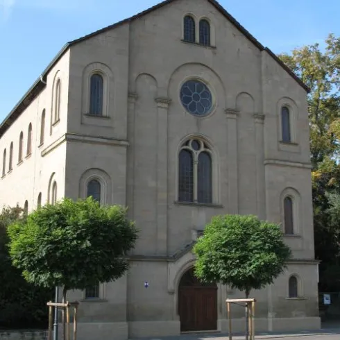 Ein lächelnder Musiker steht an einem Klavier. Die Perspektive zeigt die Innenseite des Klaviers und vermittelt eine freundliche Atmosphäre.