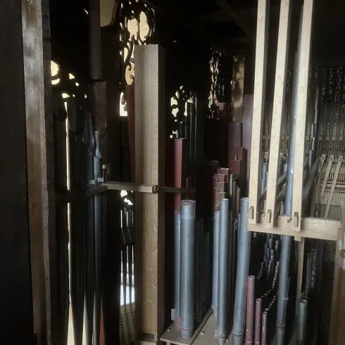 Eine Orgel mit verschiedenen Pfeifen in unterschiedlichen Farben und Größen. Die Struktur ist aus Holz und zeigt kunstvolle Details.