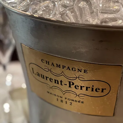 Ein stilvoller Eiskübel mit Laurent-Perrier Champagner. Umgeben von Gläsern für eine festliche Atmosphäre.