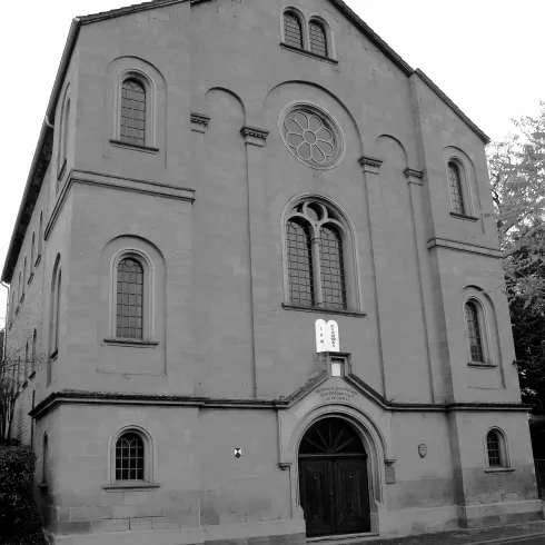 Eine beeindruckende Steinstruktur mit konservativem Design und großen Fenstern. Das Gebäude hat eine historische Ausstrahlung und befindet sich in einem ruhigen Umfeld.