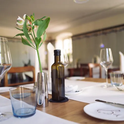 Ein eleganter Tisch in einem Restaurant, dekoriert mit einem Blumenstrauß und Glasware. Die Atmosphäre ist freundlich und einladend.