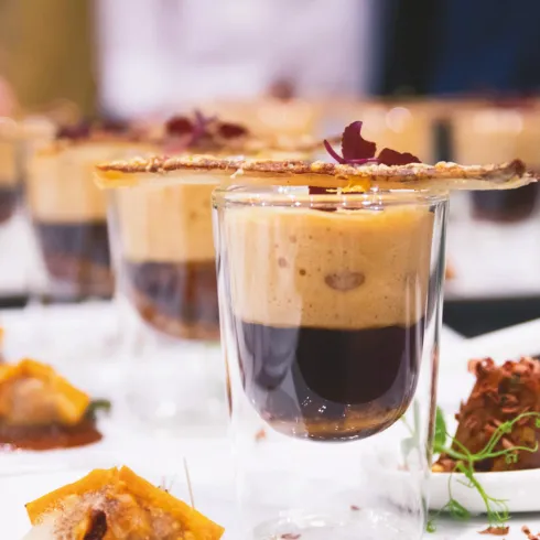 Ein ansprechendes Dessert in Gläsern, geschichtet mit Schokolade und Kaffee. Garnierungen und kleine Häppchen sind auf dem Teller angerichtet.