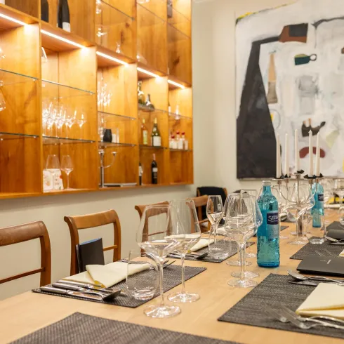 Ein stilvoll eingerichteter Tisch in einem Restaurant, dekoriert mit Gläsern und Flaschen. Im Hintergrund hängt ein modernes Kunstwerk an der Wand.