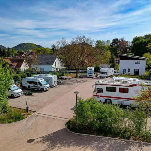 Ein Campingplatz mit mehreren Wohnmobilen und Wohnwagen. Umgeben von Bäumen und einer ruhigen Landschaft.