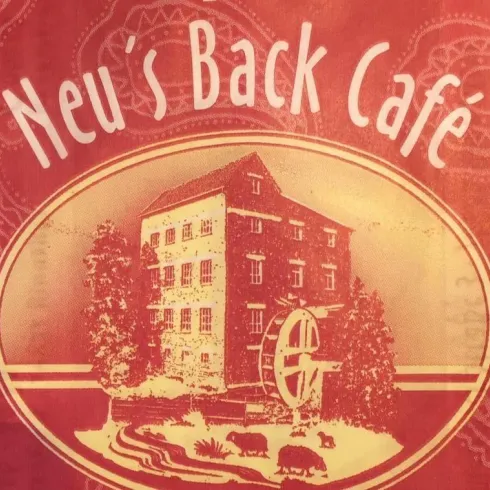 Ein altehrwürdiges Café mit dem Namen "Neu's Back Café" ist abgebildet. Im Hintergrund sieht man ein traditionelles Gebäude und eine ländliche Szene.