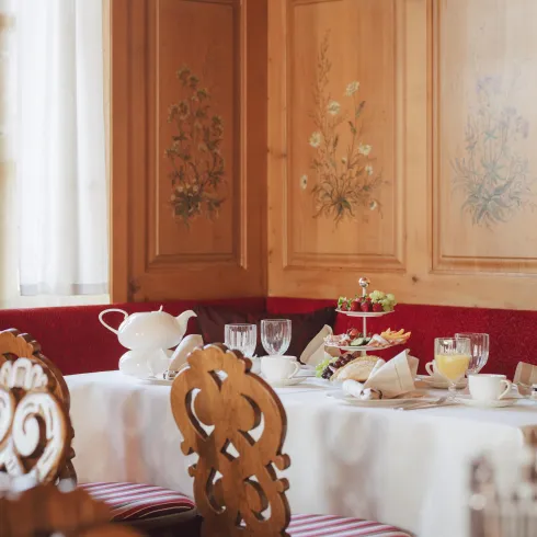 Ein einladender Essbereich mit dekorierten Holzwänden. Der Tisch ist festlich gedeckt mit Geschirr und frischen Speisen.