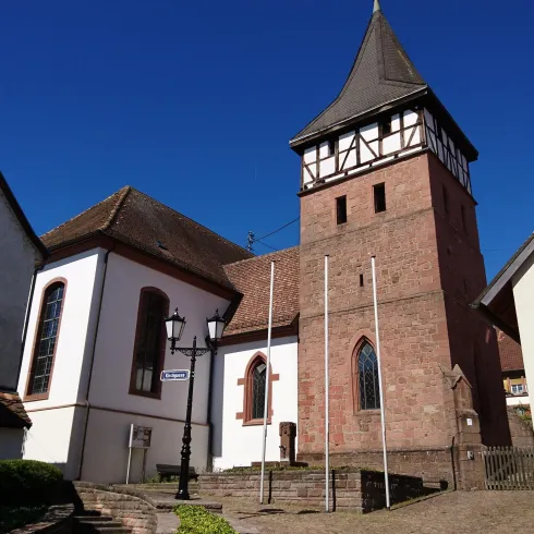 Eine alte Kirche mit einem markanten Turm und weißen Wänden. Der klare blaue Himmel sorgt für eine schöne Kulisse.
