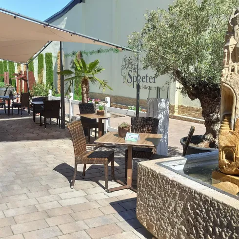 Im Vordergrund steht eine aus Stein gemeiselte Stadt, in einem Brunnen voll Wasser. Im Hintergrund asieht man die Terasse des Restaurants.