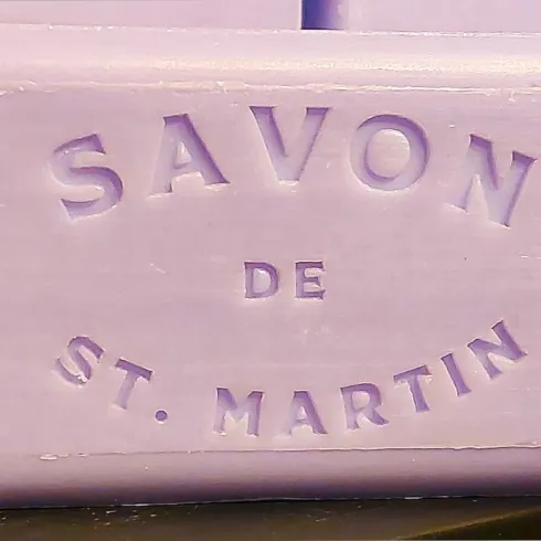 Ein Stück lila Seife mit der Aufschrift "Savon de St. Martin". Die Seife hat eine glatte Oberfläche und scheint handgemacht zu sein.
