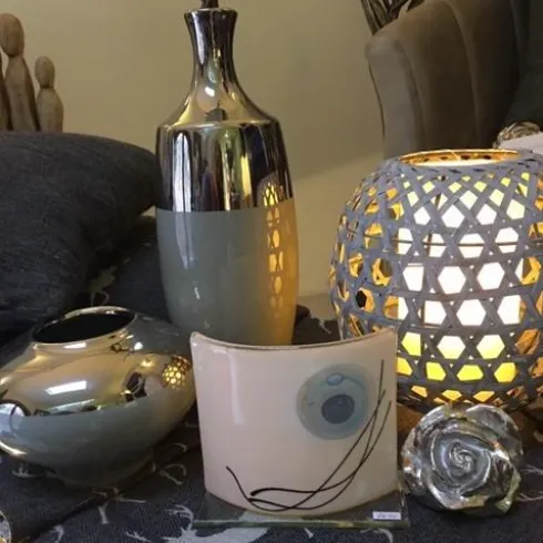 Dekorative Vasen und ein stilvolles Teelicht auf einem Tisch. Die Kombination aus modernen Formen und sanften Farben schafft eine gemütliche Atmosphäre.