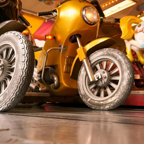 Zwei Spielzeugmotorräder stehen auf einem Jahrmarkt. Die goldene Maschine und eine schwarze Maschine sind bereit für Kinder.