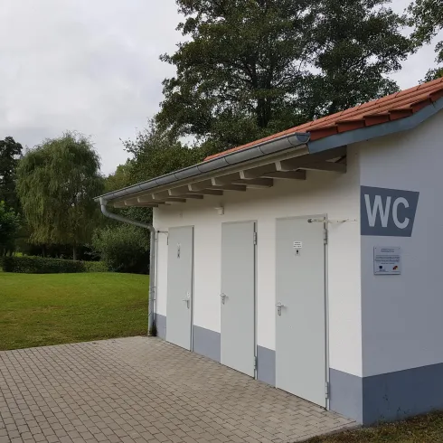 WC-Anlage im Hintergrund der Wohnmobilstellplatz