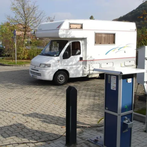 Ein Wohnmobil steht auf einem Parkplatz. Neben dem Wohnmobil befindet sich ein nützlicher Serviceautomaten.