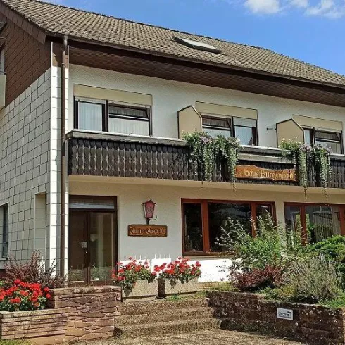 Ein schönes, zweigeschossiges Haus mit einem Balkon und blühenden Pflanzen. Der Eingangsbereich ist einladend und gut gepflegt.