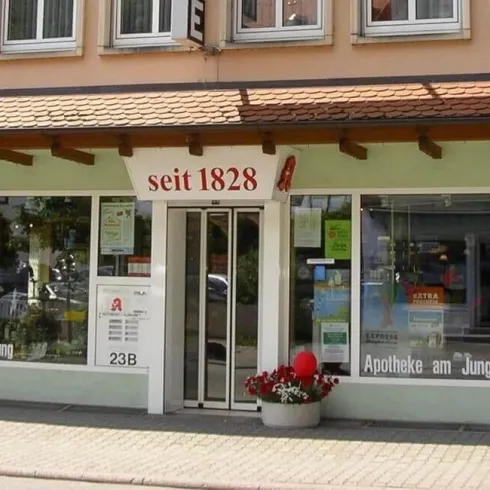 Ein Geschäft mit großer Fensterfront, das „seit 1828“ eröffnet wurde. Vor dem Eingang befinden sich Blumen und bunte Dekorationen.