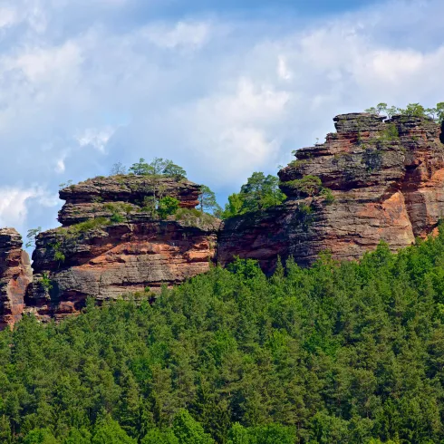 Eine beeindruckende Felsformation mit bewaldeten Hängen. Der Himmel ist bewölkt und verleiht der Landschaft eine dramatische Stimmung.