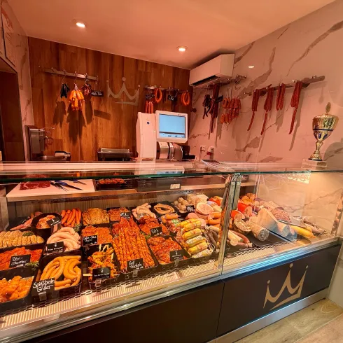 Ein eleganter Fleischereibereich mit einer Vielzahl von frischen Fleischwaren und Wurstprodukten. Die Vitrine ist gut beleuchtet und ansprechend präsentiert.