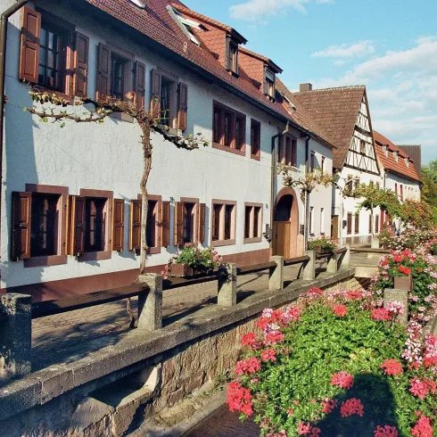 Ein malerisches Dorf mit traditionellen Fachwerkhäusern und bunten Blumen. Die ruhige Straße lädt zum Spazieren ein.